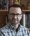 photograph of Eric Nigh in front of a bookshelf