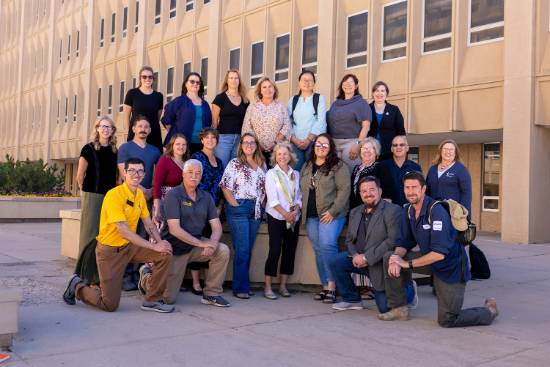 A group of people smiling and posing for a photo in front of a building on the UW campus.