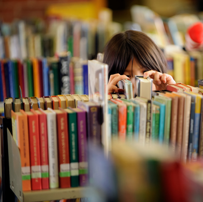 An elementary school student searches though library shelves