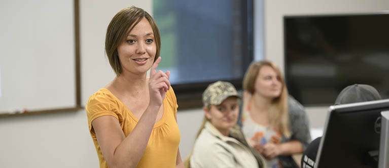 A female student leads a class in a computer lab