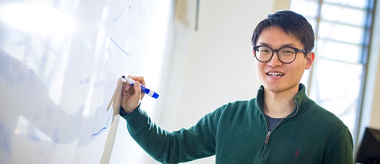 A male student writes on a white board