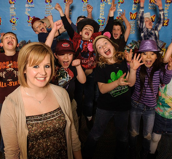 A teacher stands with her class of young children