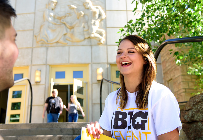 A female student laughs with friends outside of the Education Building