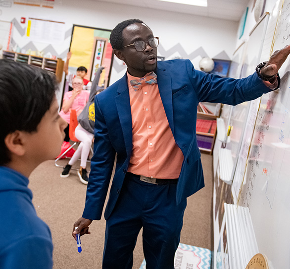 Teacher explaining something on the board to a student