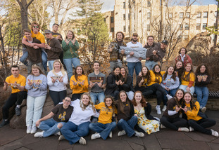 A group of Cowboy Coaches, peer mentors, pose and smile outside on the University of Wyoming campus.