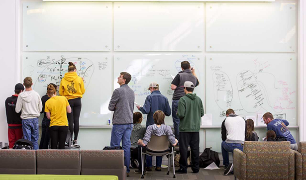 image of students working together on a board