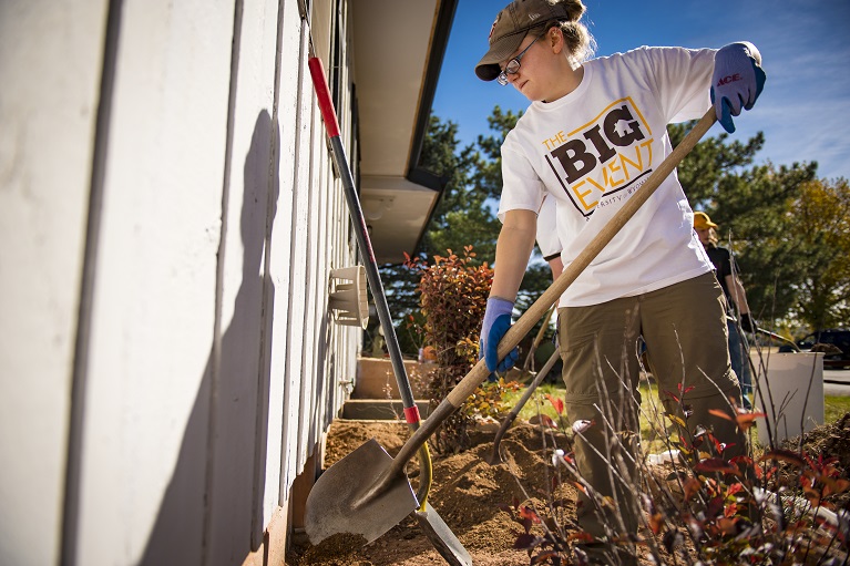 a student with a shovel working on landscaping