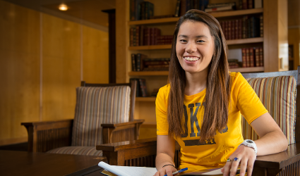 Student in library with book open on their lab