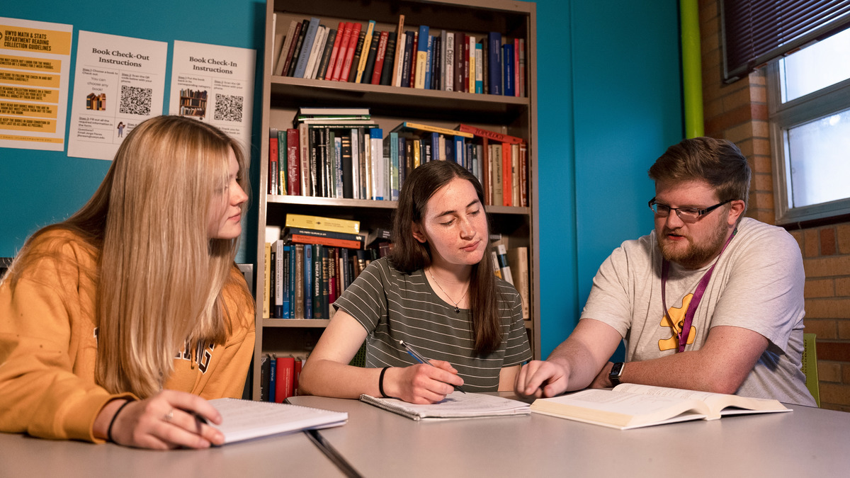 Two students meet with an advisor in a campus office