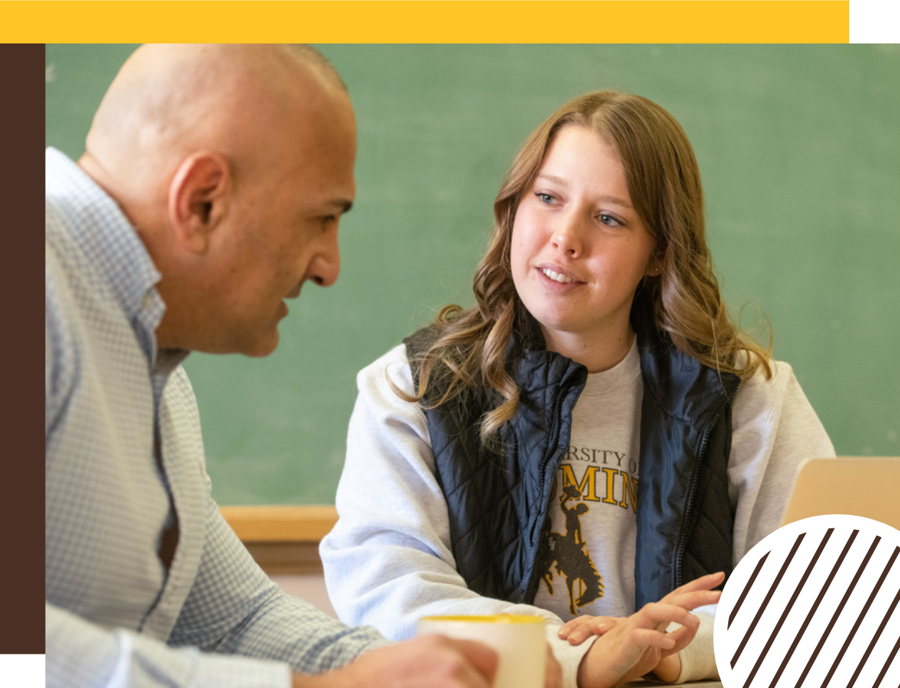 A student meets with a faculty member and working on a laptop