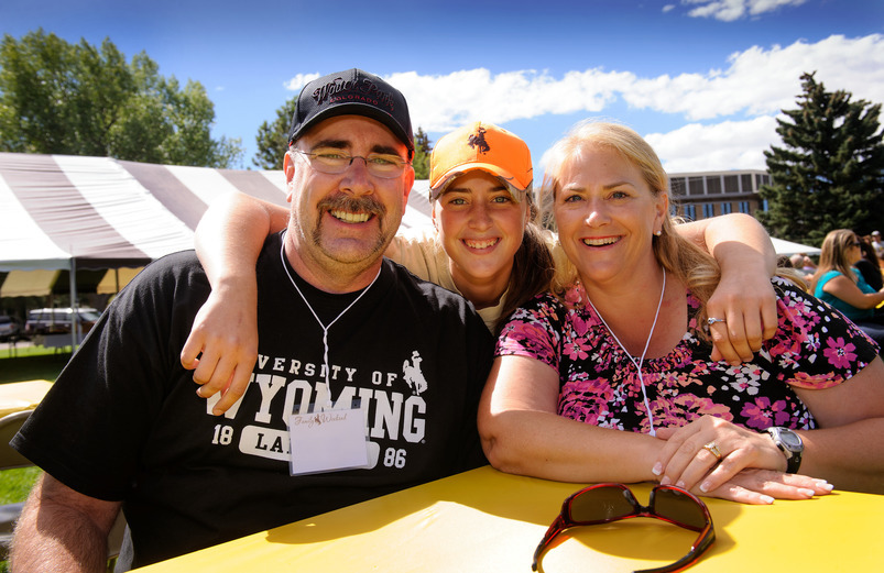Student poses with parents at campus event