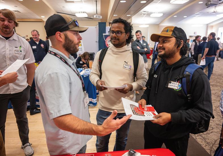 Two students chat with a staff member at a Union Event