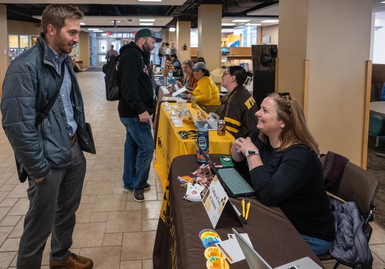 Student meets with staff member at tabling event