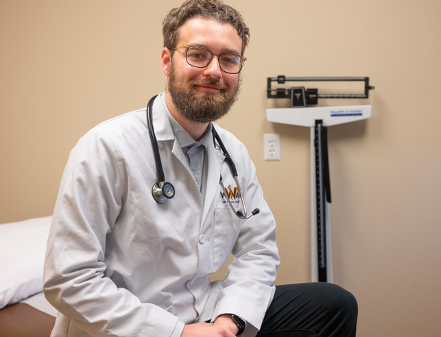 Doctor sits on table in front of scale
