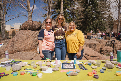 Two students posing behind event table