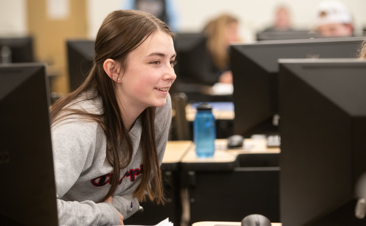 Student smiling looking at a computer