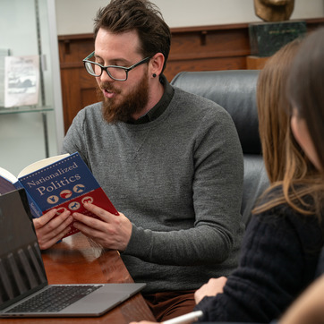 Student reading from a book in front of a class
