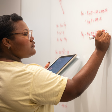 Student writing at a white board