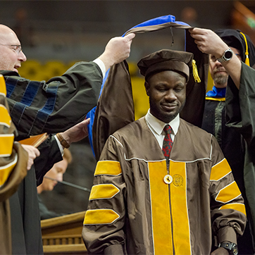 UW Student being hooded for a PhD at Commencement