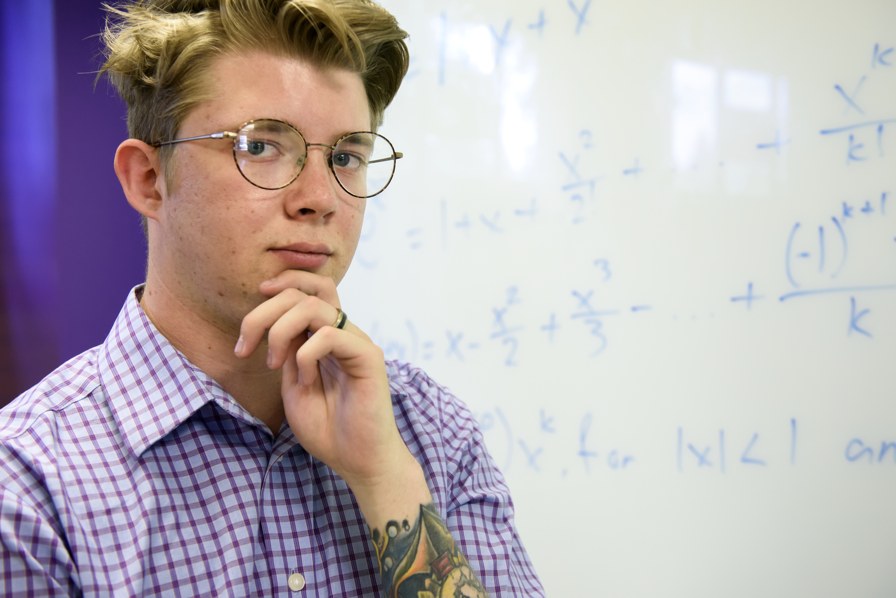 Math student ponders in front of a white board with math work