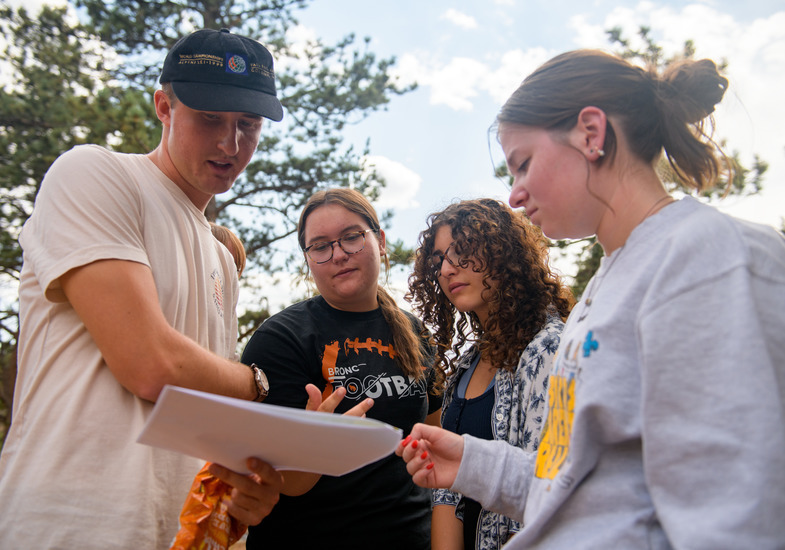 A group of four students look at directions outside.