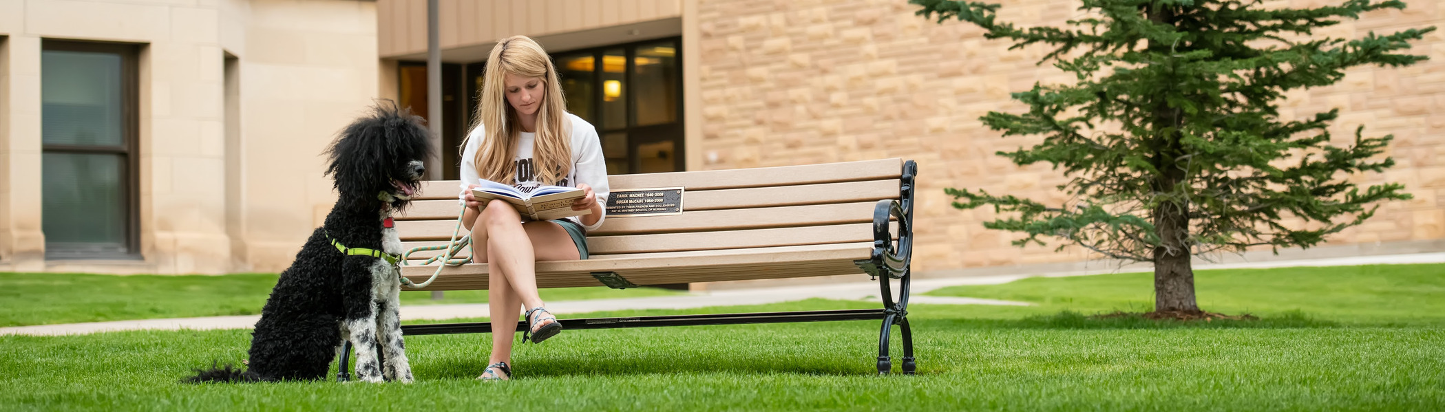 Student reading outside with dog