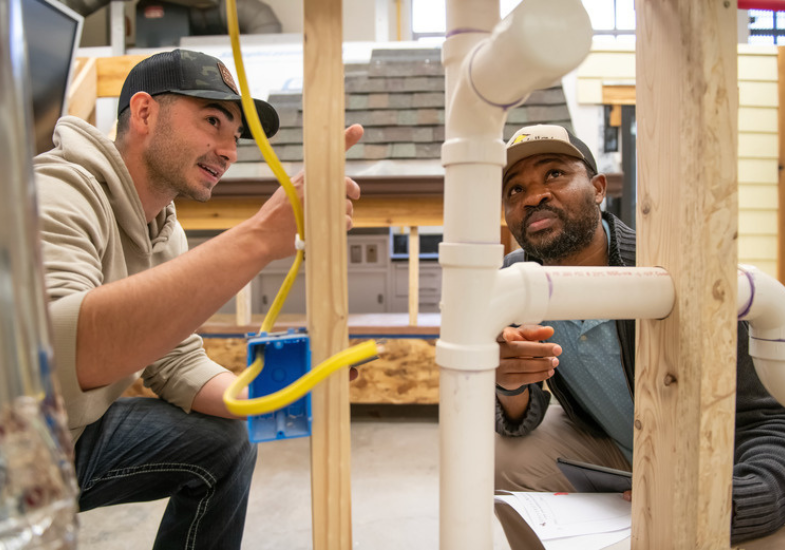 two students looking at plumbing in house