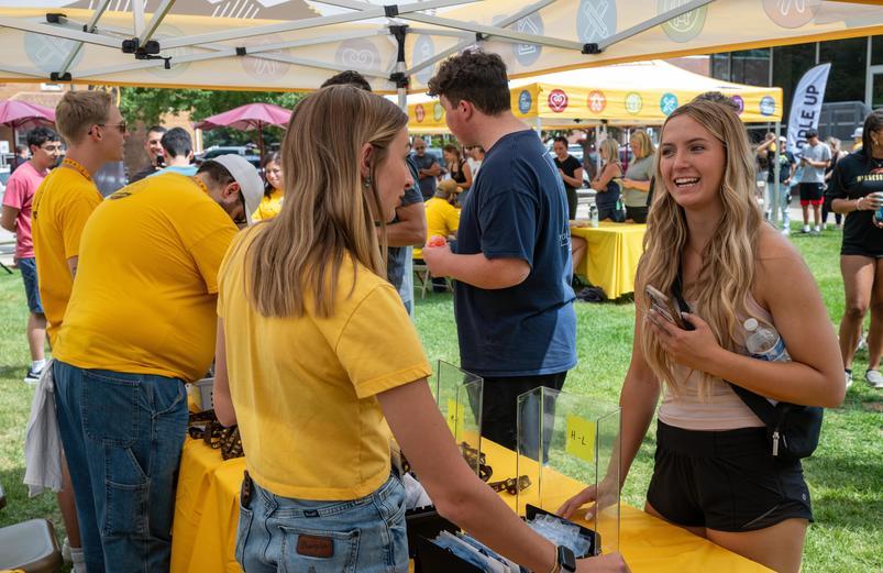 students talk with reps at a table.