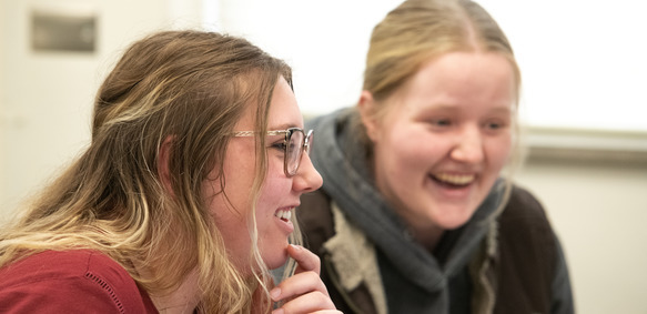 Two UW students smile as they work on computers during a University of Wyoming class.