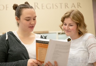 A UW student and staff member discuss course offerings at the Office of the Registrar.