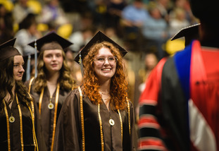 A UW student smiles as they prepare to cross the stage at a University of Wyoming graduation ceremony.