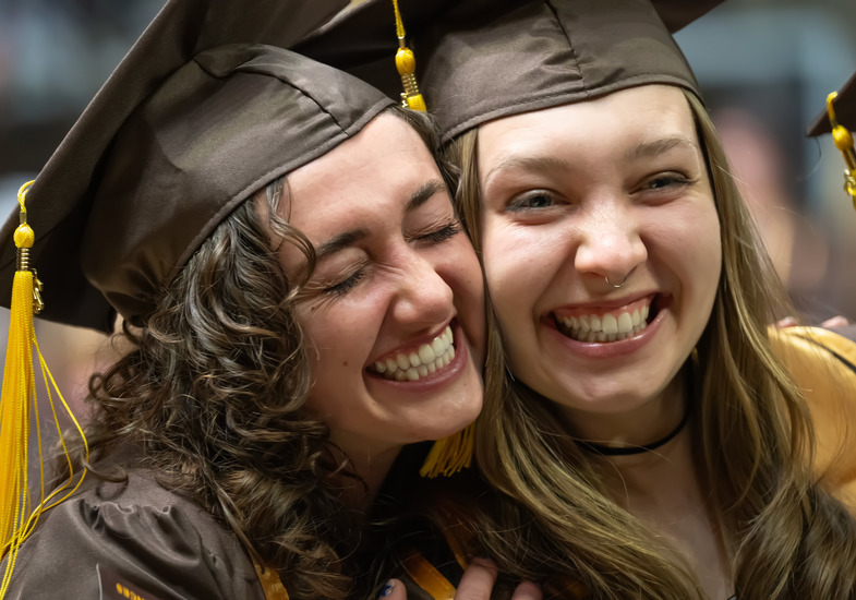 Two UW students smile at a University of Wyoming graduation ceremony.
