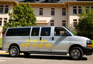 A University of Wyoming fleet van vehicle with "The World Needs More Cowboy" written on the side.