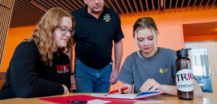 Three people looking over a folder 