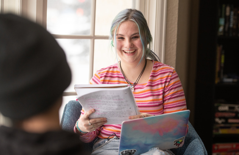 Student smiling and holding notebook