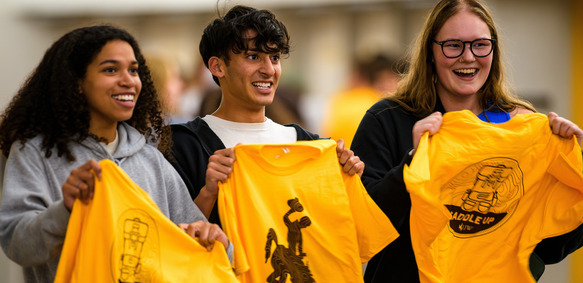 Three students proudly hold up new University of Wyoming apparel.