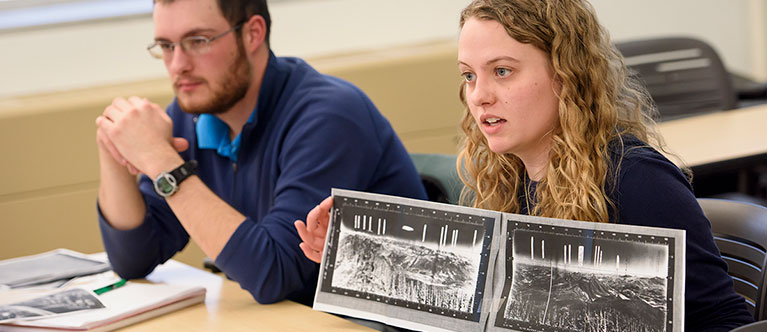 A woman displays an image while presenting with her classmate.