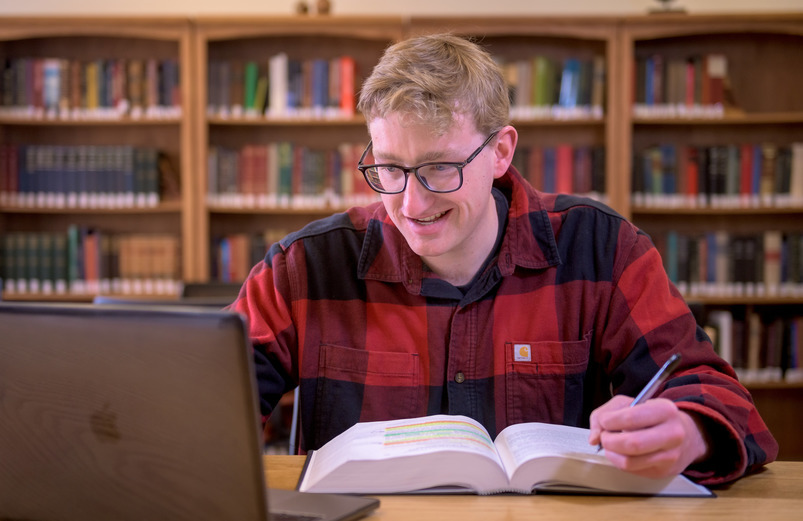 stuednt studies with a textbook and computer