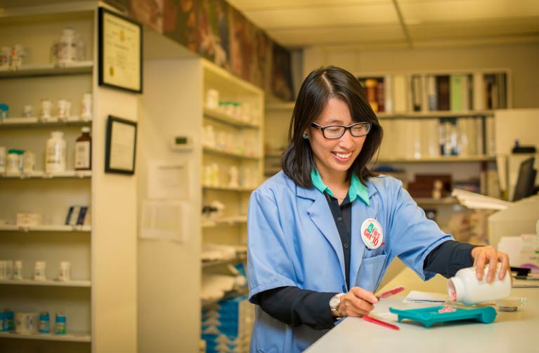 Pharmacy student working behind pharmacy counter