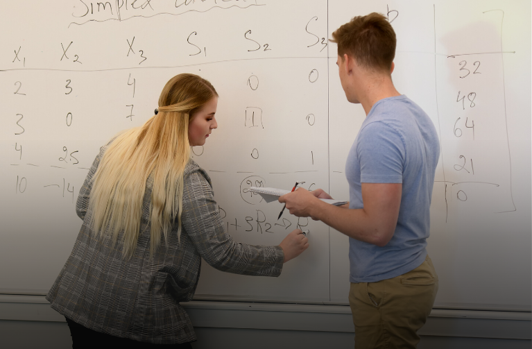 Student helping other student on a white board
