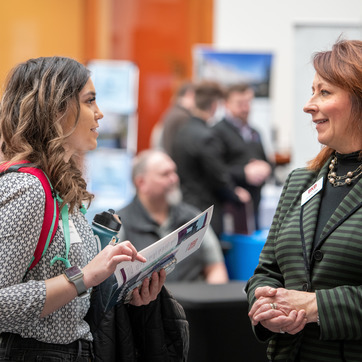 A UW student and faculty member discuss University of Wyoming college options at a UW event.