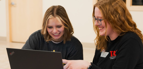 UW student and staff member smile as they work together on a computer.