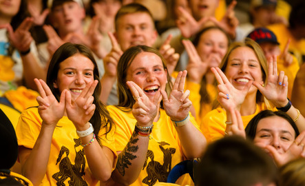 A trio of UW students happily make a “W” with their fingers at a UW admissions event.