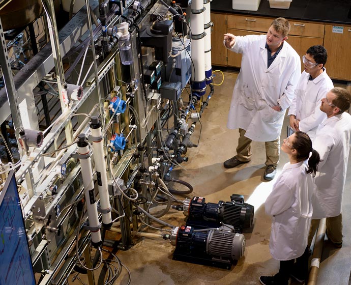 people in white coats looking at equipment