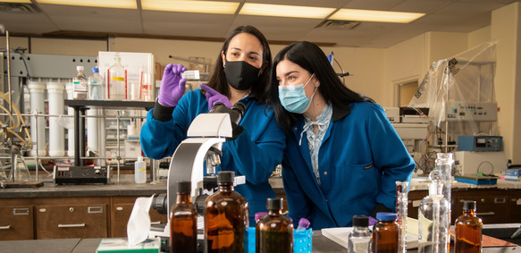 two student in a lab looking at a microscope slide