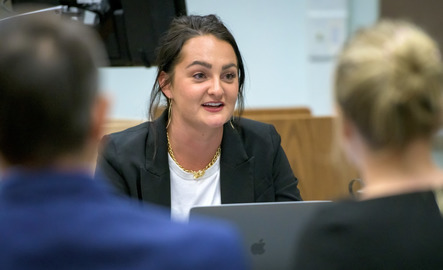 A student on a laptop talking to classmates