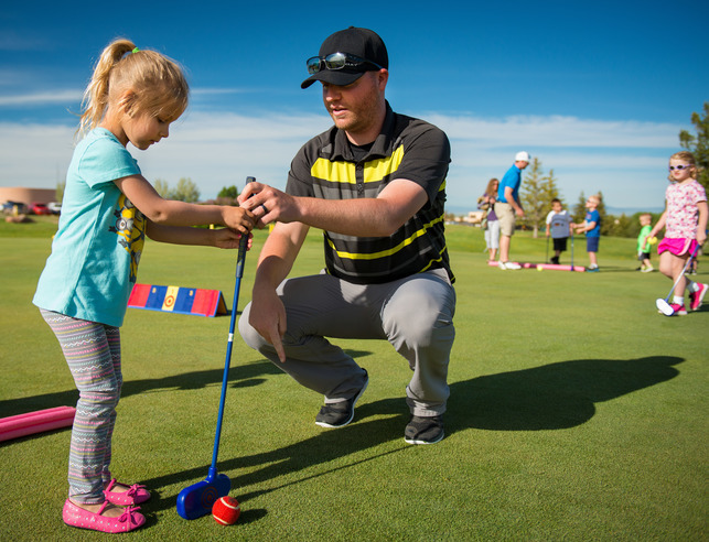 Teacher helping young student golf.
