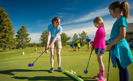 Teacher helps young students play golf.