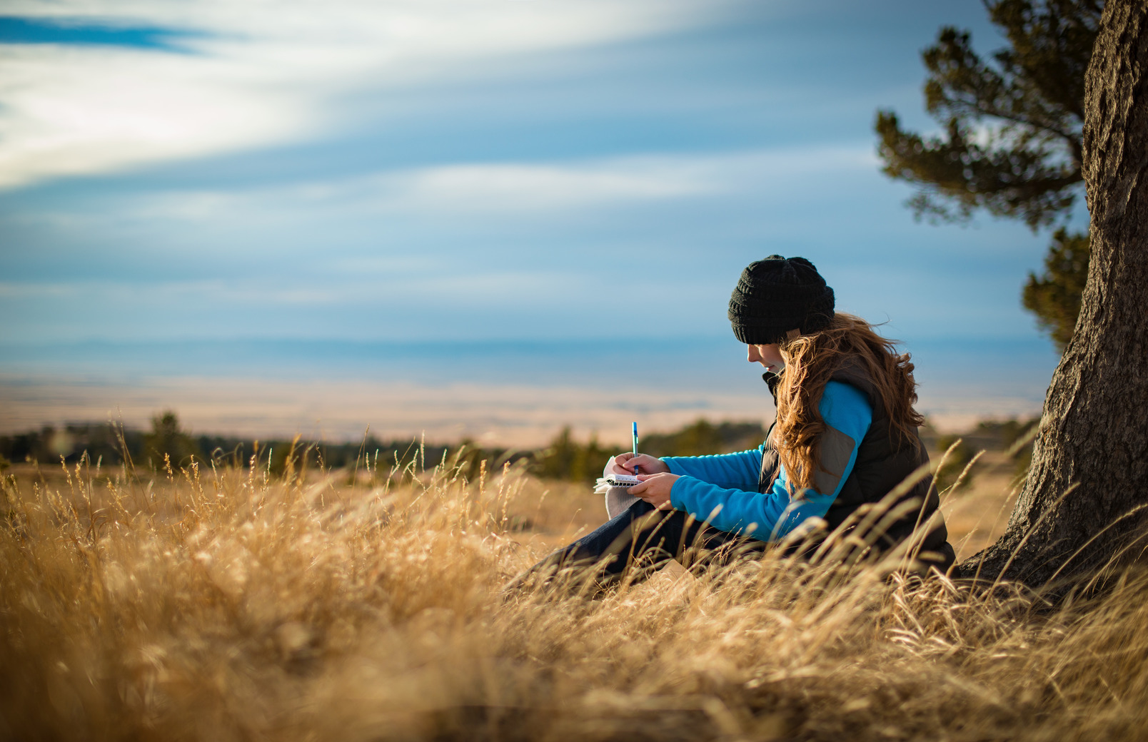 Student writing in notebook in a field