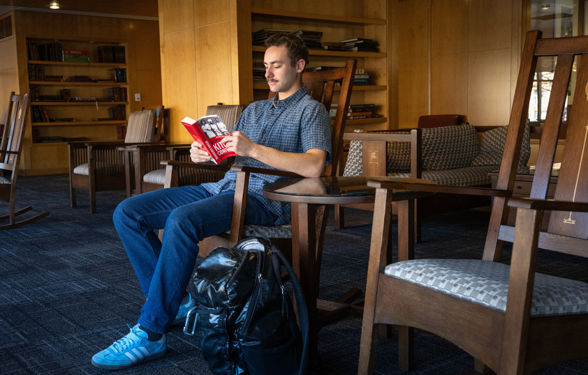 A student reads a book in a rocking chair